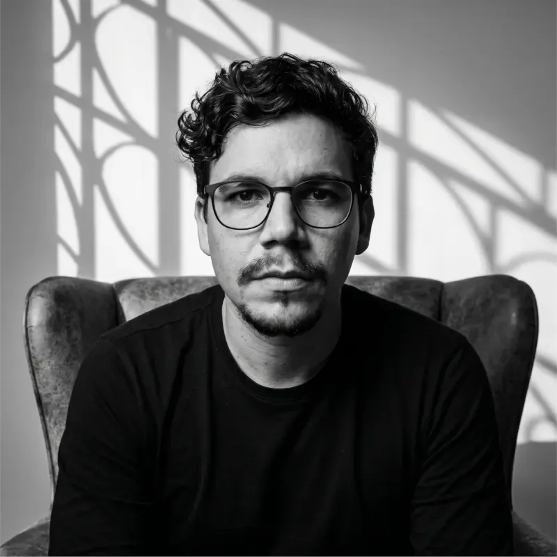 Retrato em preto e branco de Wesley Hudson, fundador da WHE Studio, sentado em uma poltrona.